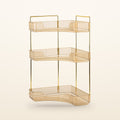 Gold 3-tier corner bathroom counter organizer with amber trays on a cream background