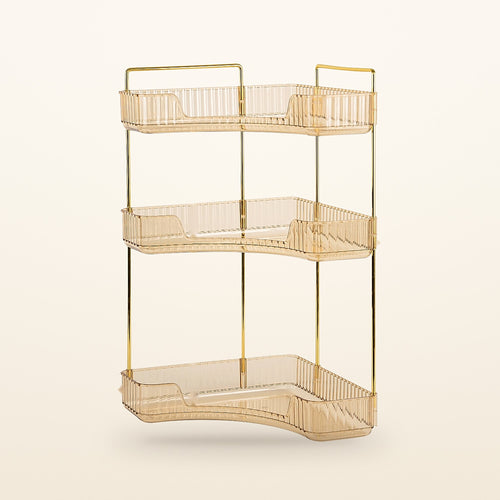 Gold 3-tier corner bathroom counter organizer with amber trays on a cream background