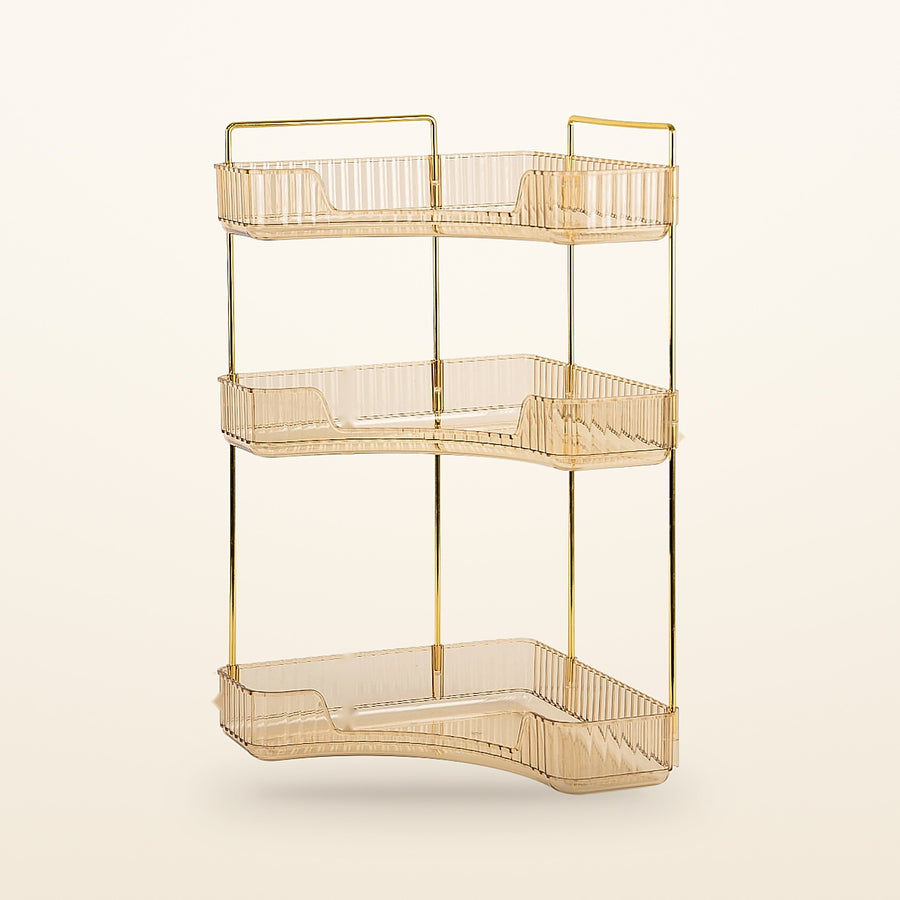 Gold 3-tier corner bathroom counter organizer with amber trays on a cream background