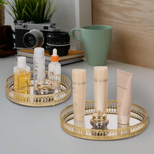 Two gold mirrored vanity trays with skincare tubes and bottles on a desk