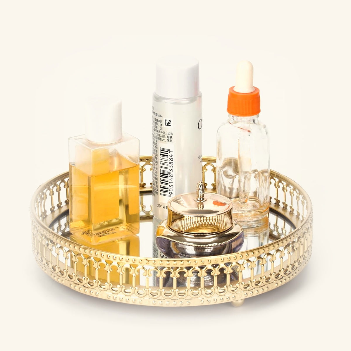 Small round gold mirrored vanity tray holding perfume and skincare bottles